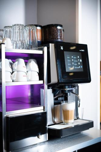 a coffee maker with a cup on a counter at Taste Hotel Hockenheim in Hockenheim