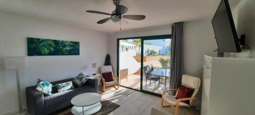 - un salon avec un canapé et un ventilateur de plafond dans l'établissement Lanzarote-Beach-Apartment, Las Cucharas Beach, Costa Teguise -- 1 MINUTE WALK FROM MAIN SQUARE, 35 METERS FROM BEACH, à Costa Teguise