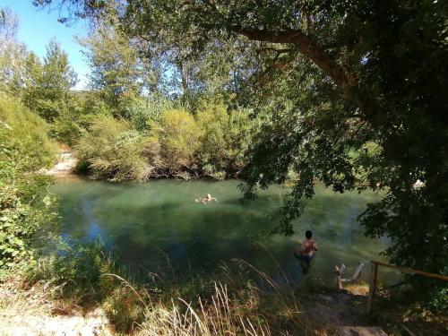 Un homme debout dans l'eau dans un lac dans l'établissement Villa Ripaud, private river swimming, hot tub, à Villesèque-des-Corbières