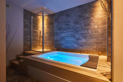 a tub in a bathroom with a stone wall at Castelmartini Wellness & Business Hotel in Larciano