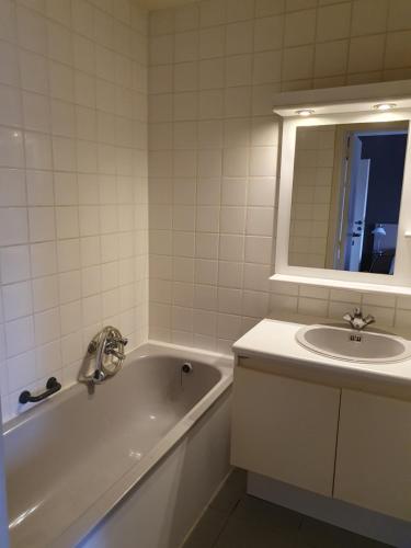 a white bathroom with a tub and a sink at Carré in Lommel