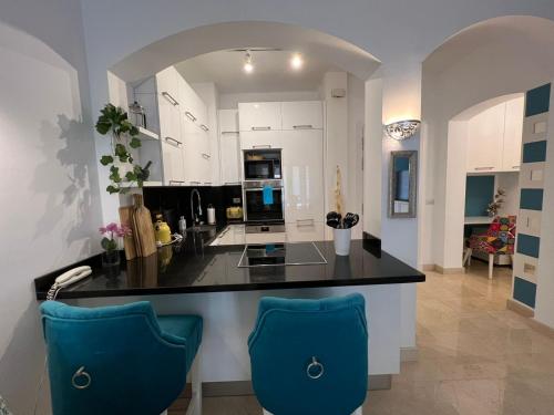 a kitchen with a black counter and two blue chairs at El gouna Ferienwohnung in zentraler Lage in Hurghada