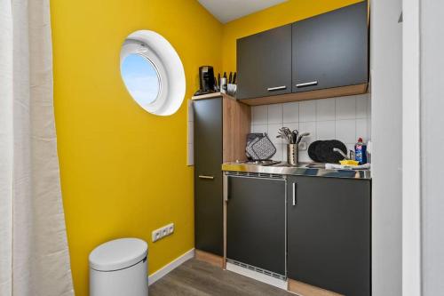 uma cozinha com paredes amarelas e um frigorífico preto em Grünes Wohnen in Düren em Düren - Eifel