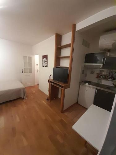 Cette chambre comprend un lit et un bureau avec une télévision. dans l'établissement STUDIO PARIS BASTILLE, à Paris