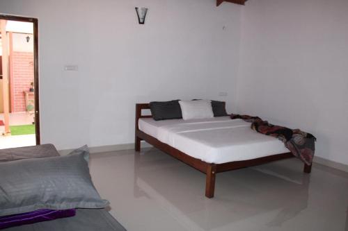 a bed in a room with a white wall at Coorg Happy Estate Stay in Madikeri