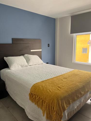 Un dormitorio con una cama grande con una manta amarilla. en Apartamento en Condominio Privado, en Quetzaltenango