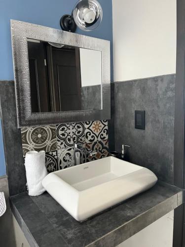 baño con lavabo blanco grande y espejo en Apartamento en Condominio Privado, en Quetzaltenango