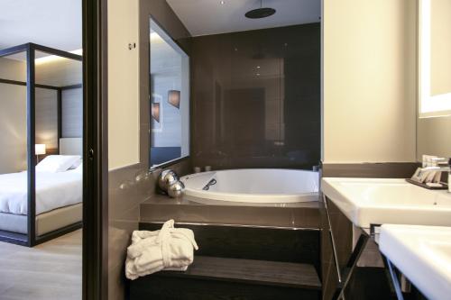 a bathroom with a tub and two sinks and a bed at Ego Hotel in Ancona