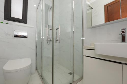 a bathroom with a shower and a toilet and a sink at Empire Apartments in Juffair