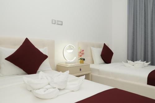 a bedroom with two beds with white and brown pillows at Empire Apartments in Juffair