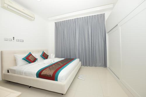 a white bedroom with a bed and a window at Empire Apartments in Juffair