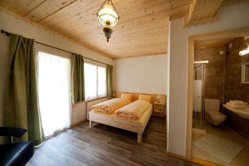 a bedroom with a bed and a bathroom with a window at Hotel Gemse in Weisstannen