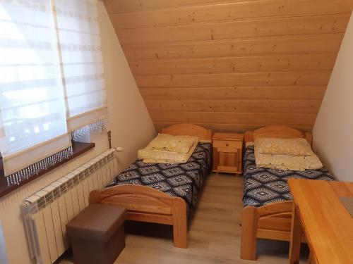 2 łóżka w pokoju ze stołem i krzesłami w obiekcie Pokoje u Lusi w mieście Białka Tatrzanska