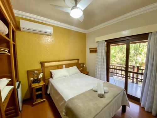 a bedroom with a bed and a window with a balcony at Pousada Gramado in Gramado