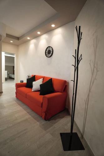 a red couch in a room with a clock on the wall at Modern Apartment on the Mt.Baldo & Garda Lake in Brentonico