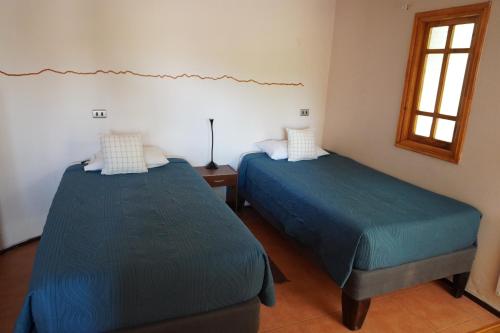 a room with two beds and a window at Hotel-Camping Takha Takha in San Pedro de Atacama