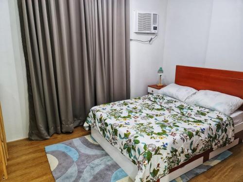 a bedroom with a bed with a floral comforter at Mesatierra Garden Residences in Davao City