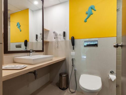 a bathroom with a sink and a toilet and a mirror at Acron Seaway Resort in Candolim