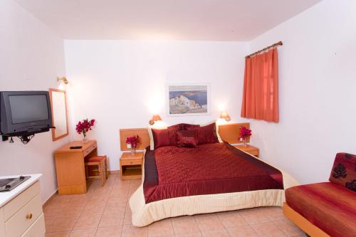 a bedroom with a red bed and a tv at Anastasia Studios Lindos in Líndos