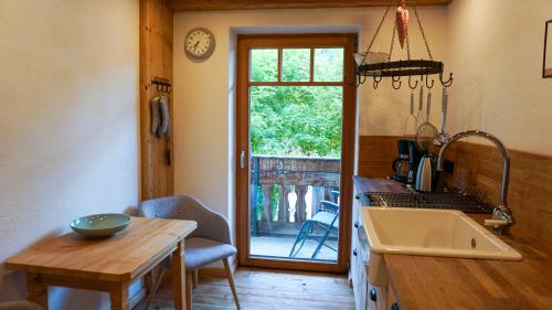 eine Küche mit einem Waschbecken, einem Tisch und einem Fenster in der Unterkunft Haus Petra in Bach