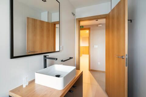 łazienka z białą umywalką i lustrem w obiekcie APARTAMENTOS LAS OLAS BY PANTIN w mieście Valdoviño