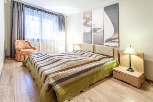 een slaapkamer met een bed, een stoel en een raam bij Apartamenty Zielone Tarasy - visitopl in Kołobrzeg