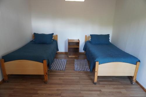 two beds in a small room with blue pillows at Hotel-Camping Takha Takha in San Pedro de Atacama