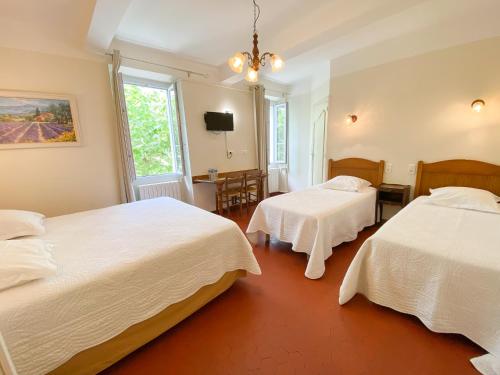 um quarto de hotel com duas camas e uma televisão em Logis Grand Hotel Bain em Comps-sur-Artuby