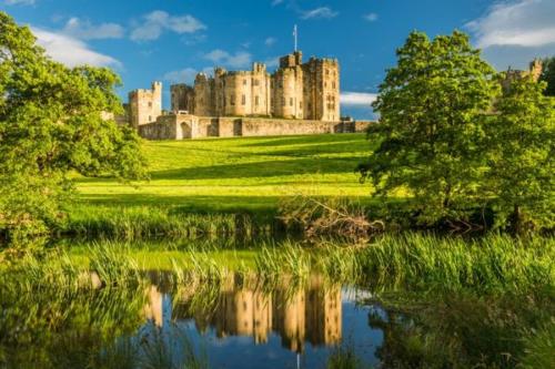 a castle sitting on top of a lush green field at Angel Lane Alnwick Apartment in Alnwick