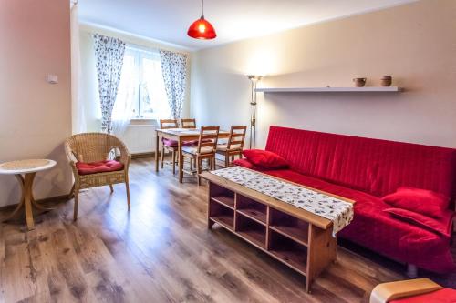 een woonkamer met een rode bank en een tafel bij Apartamenty Zielone Tarasy - visitopl in Kołobrzeg