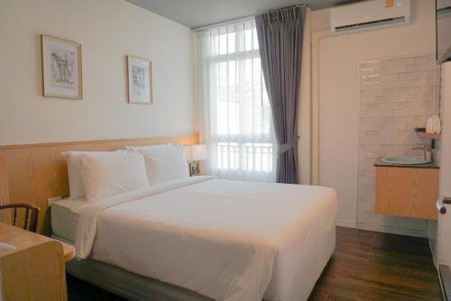 a bedroom with a large white bed and a window at Ago Hotel Chinatown in Bangkok