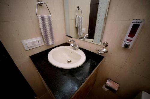 ein Badezimmer mit einem weißen Waschbecken und einem Spiegel in der Unterkunft SKY TOUCH COTTAGES AND STAYS UNIT 2 in Mukteswar