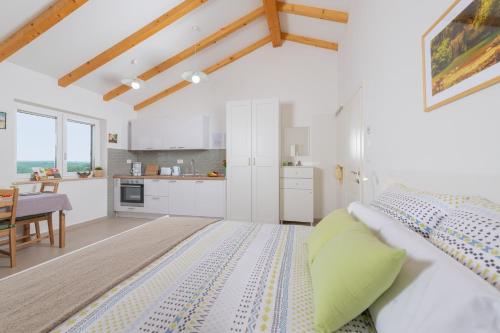 um quarto branco com uma cama e uma cozinha em Studio LOVOR in the Green Countryside of Central Istria em Tinjan