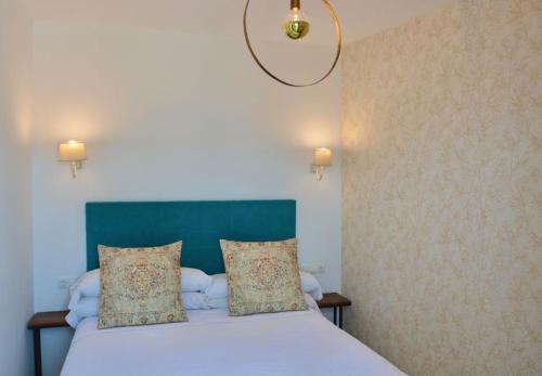 1 dormitorio con 1 cama con cabecero azul y 2 almohadas en Piso Al Lago - Appartment with Fabulous Lake Views en Zahara de la Sierra