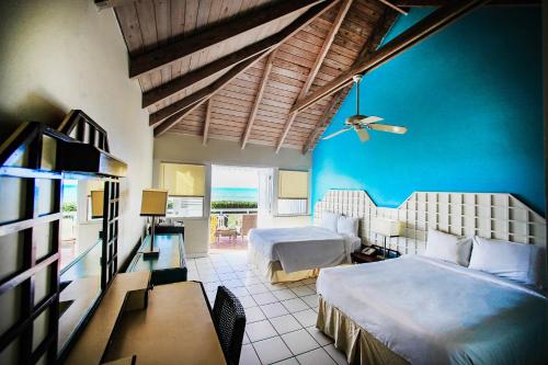 a bedroom with two beds and a blue wall at Hawksbill Resort Antigua - All Inclusive in Five Islands Village