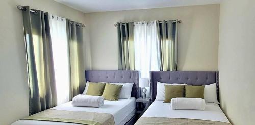 two beds in a room with two windows at Paradise Oasis at Oceanpointe - pool and free parking in Lucea