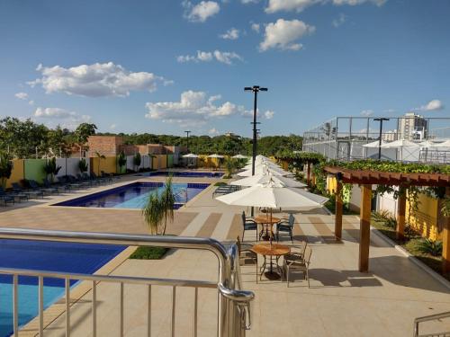 un patio con mesas y una sombrilla junto a la piscina en RECANTO DO BOSQUE _R3CALDAS, en Caldas Novas