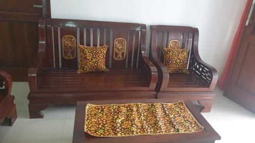 2 bancos de madera con almohadas de leopardo en una habitación en Richandy House - 3 BR Full AC & Hot Water, en Kejayan