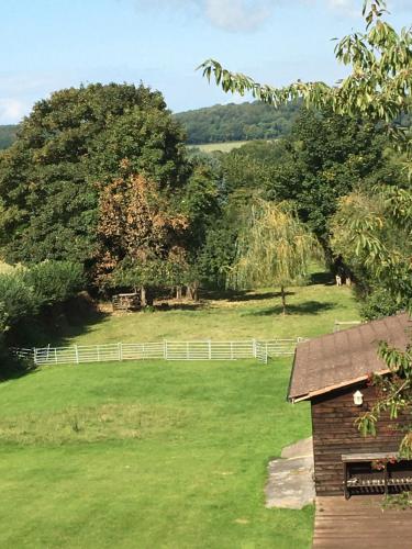 ein Feld mit einem weißen Zaun und einem Haus in der Unterkunft The Loft at Pen Orchard in Winscombe