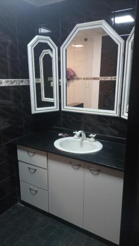 uma casa de banho com um lavatório e 2 espelhos em CABAÑAS VILLA CLUB 3 cerca del aeropuerto el palomar em Hurlingham