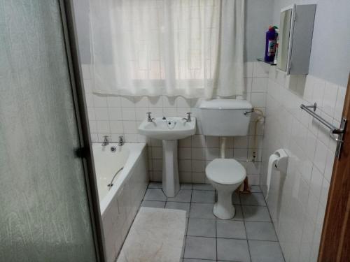 La salle de bains est pourvue d'un lavabo, de toilettes et d'une baignoire. dans l'établissement Ezrom bright, à Port Shepstone