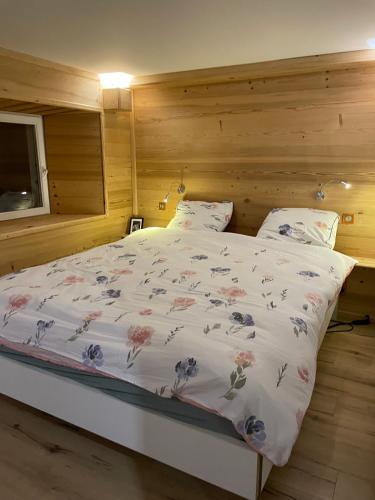 une chambre avec un lit avec une couette fleurie dans l'établissement L'etoile du matin, à Châtel