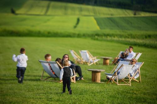 grupa ludzi siedzących w fotelach na polu w obiekcie Biała Akacja Resort & Business w mieście Prudnik