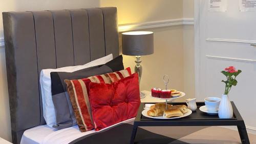 Una cama con una mesa con platos de comida. en Prime Inn, en Londres