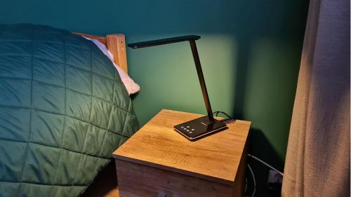 a lamp on a wooden table next to a bed at Spokojny Wypoczynek 4 in Ostrów Wielkopolski