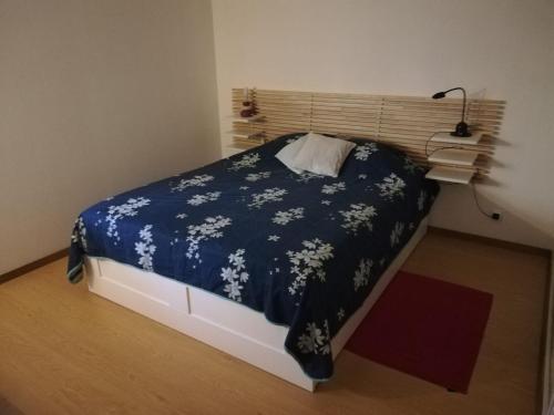 - une chambre dotée d'un lit avec une couverture bleue et des fleurs blanches dans l'établissement Appartement T2 Ax-les-thermes, à Ax-les-Thermes