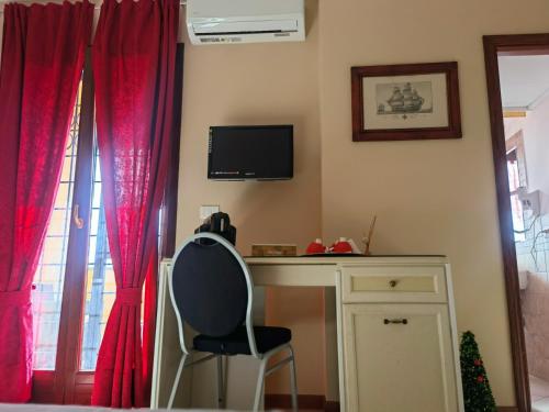 a desk and a chair in a room with red curtains at Fiumicino Inn Airport in Fiumicino