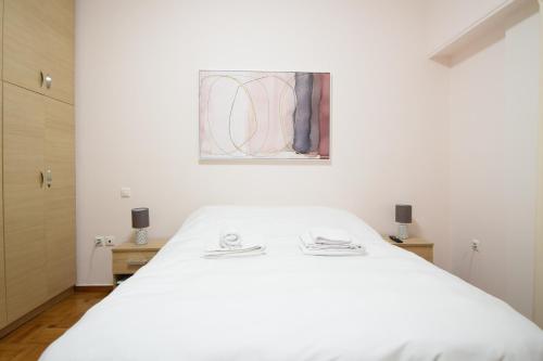 アテネにあるacropolis super cosy apartmentの白いベッドと壁に絵画が飾られたベッドルーム1室
