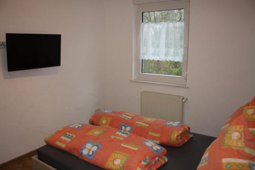a bedroom with two beds and a television on the wall at Chiaras Ferienwohnung in Heusweiler