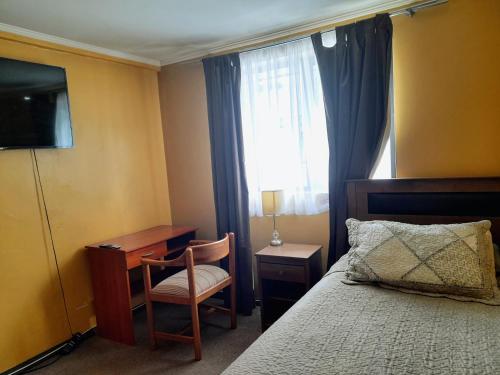 1 dormitorio con cama, escritorio y ventana en Big Attico, en Puerto Montt